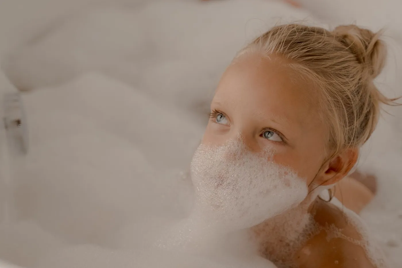 Jeune enfant qui joue joyeusement dans un bain rempli de mousse et de bulles